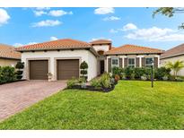 Charming one-story home with a well-manicured lawn, brick driveway, and a two-car garage at 10120 Carnoustie Pl, Bradenton, FL 34211