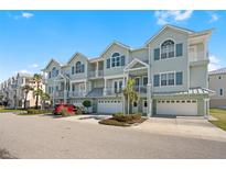 Three-story building with light green exterior, multiple garages, and landscaping at 10390 Longshore # 83, Placida, FL 33946