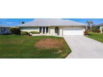 Charming single-story home featuring a well-maintained lawn and a two-car garage and beautifully manicured landscaping at 31 Bunker Pl, Rotonda West, FL 33947