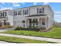 Two-story house with gray siding, gray shutters, landscaping, and a two-car garage at 5307 Grove Mill Loop, Lakewood Ranch, FL 34211