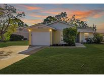 Inviting yellow house with a white garage door and landscaped lawn at 6507 36Th Avenue W Dr, Bradenton, FL 34209