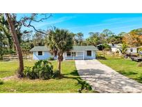 Charming single-story home with a gravel driveway, lush lawn, and a welcoming porch at 712 N Elm St, Englewood, FL 34223