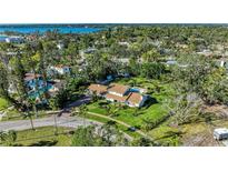 Expansive aerial view of a property with lush landscaping, pool, and well-maintained lawn near the water at 7820 Seville Cir, Bradenton, FL 34209