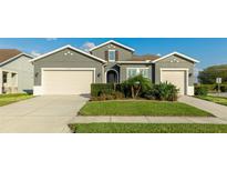 Two-story house with gray siding, beige garage doors, and manicured landscaping at 1115 116Th E St, Bradenton, FL 34212