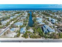Waterfront homes line a canal leading to the open ocean in this sunny aerial view at 9205 Gulf Dr, Anna Maria, FL 34216