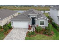 Gray house with white garage door, landscaping, and a paved driveway at 17723 Gulf Ranch Pl, Lakewood Ranch, FL 34211