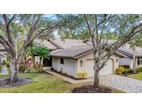 Charming single-story home featuring a well-manicured lawn, mature trees, and a paver driveway at 5653 Pipers Waite # 26, Sarasota, FL 34235