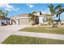 Tan single-story house with a three car garage and lush landscaping at 12822 Rainwashed Loop, Parrish, FL 34219