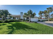 Inviting home with a manicured lawn, lush tropical landscaping, and a basketball court for Gathering fun at 1302 Roberts Bay Ln, Sarasota, FL 34242