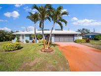 Single-story home with gray exterior, palm trees, and a red driveway at 157 Da Vinci Dr, Nokomis, FL 34275