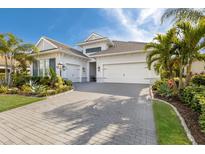 Beautiful single-Gathering home featuring a three-car garage, lush landscaping, and a brick driveway at 16730 Collingtree Xing, Lakewood Ranch, FL 34202