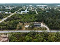 An aerial view shows this house with an expansive lot surrounded by lush greenery and proximity to community waterways at 17555 Lake Worth Blvd, Port Charlotte, FL 33948