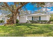 Charming single-story home featuring a well-manicured lawn, lush landscaping, and a quaint white exterior at 1873 University Pl # 135, Sarasota, FL 34235