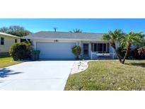 Single-story house with a white exterior, attached garage, and landscaped lawn at 2701 Larkspur Dr, Punta Gorda, FL 33950