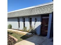 Exterior view of a condo with a gray roof, light gray walls, and landscaping at 4160 Fruitville Rd # 32, Sarasota, FL 34232