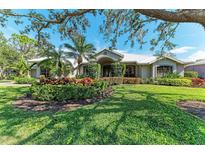 Beautiful home with manicured lawn and lush landscaping featuring colorful plants and mature trees at 4749 Antler Trl, Sarasota, FL 34238