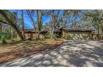 Ranch style home with green exterior, red shutters, and a large driveway at 5180 Meldon Cir, Sarasota, FL 34232