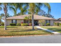 Charming single-story home with lush landscaping, palm trees, and a well-maintained lawn on a sunny day at 5507 Country Lakes Trl, Sarasota, FL 34243