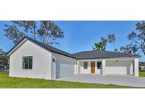 White farmhouse-style home with a dark gray roof, two-car garage, and covered porch at 5923 22Nd Avenue E Dr, Palmetto, FL 34221