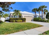 Charming single-story home featuring a lush green lawn, a well-manicured garden, and a two-car garage at 8729 52Nd E Dr, Bradenton, FL 34211