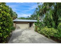 Tan house with attached garage, stone accents, and lush landscaping at 1155 Hampton Rd, Sarasota, FL 34236