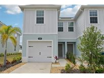 Charming townhouse with a white garage door, light blue trim, and well-maintained landscaping at 14180 Crimson Ave, Bradenton, FL 34211