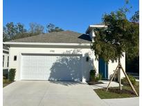 Charming single-Gathering home featuring a two-car garage, freshly landscaped yard, and a bright blue front door at 1790 White Orchid Ct, Sarasota, FL 34235