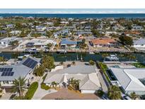 Wide aerial view of canal-front homes and Gulf, featuring docks, boats, pools, and landscaping at 627 Dundee Ln, Holmes Beach, FL 34217