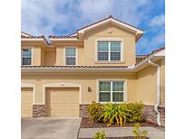 Charming townhome with tan exterior, tile roof, attached garage and nicely landscaped front entryway at 8362 Enclave Way # 103, Sarasota, FL 34243