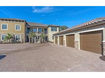 Attractive condo building exterior with garages, lovely landscaping, and stone accents at 12410 Osorio Ct # 201, Sarasota, FL 34238