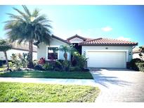 Charming single-story home with a well-manicured lawn, tropical landscaping, and a two-car garage at 12675 Richezza Dr, Venice, FL 34293