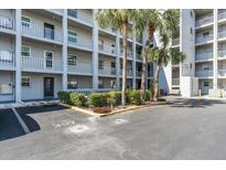 Multi-story condo building with gray exterior, white railings, tropical landscaping, and ample parking at 3050 Lake Bayshore Dr # O-108, Bradenton, FL 34205