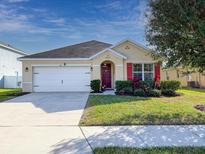 Tan house with red shutters, white garage door, and landscaped yard at 431 Gris Sky Ln, Bradenton, FL 34212