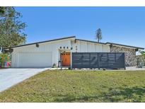 Charming single-story home features a modern design with a stone accent wall and a well-maintained lawn at 494 E Shade Dr, Venice, FL 34293