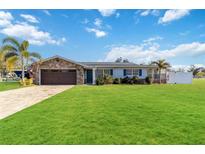 Charming single-story home featuring a stone facade, well-manicured lawn, and a paved driveway at 6001 Firefly Ln, Apollo Beach, FL 33572