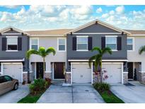 Beautiful townhome exterior features a gray facade, two-car garage, stone accents, and lovely landscaping at 8737 Daydream St, Sarasota, FL 34238