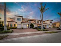 Beautiful townhome exterior with manicured landscaping, brick driveway, and attached garages, perfect for modern living at 23189 Banbury Way # 203, Venice, FL 34293