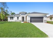 Beautiful new construction home with stone accents, a gray garage door, and a bright green lawn at 3166 Cabo St, North Port, FL 34291