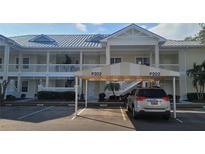 Condo building with assigned covered parking and manicured landscaping under a clear blue sky at 3706 54Th W Dr # 202, Bradenton, FL 34210