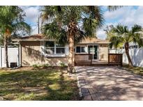 Charming bungalow with a brick driveway, a cozy deck, and lush tropical landscaping at 445 88Th N Ave, St Petersburg, FL 33702
