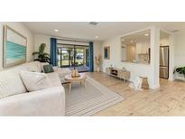 Bright living room with a comfortable sectional sofa, wood flooring, and sliding glass doors to the lanai at 536 Miro Cir # 536, Nokomis, FL 34275