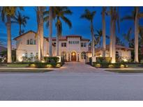 Elegant two-story home featuring lush landscaping, mature palm trees, and a beautiful paver driveway and walkway at 13315 Palmers Creek Ter, Lakewood Ranch, FL 34202