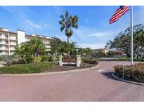 Inviting Excelsior community entrance with mature landscaping and an American flag waving in the breeze at 6263 Midnight Pass Rd # 105, Sarasota, FL 34242