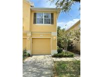 Exterior view of home featuring a one-car attached garage, yellow facade, and well-maintained landscaping at 6768 Breezy Palm Dr, Riverview, FL 33578