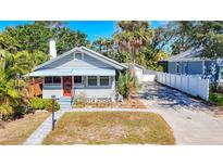 Charming cottage-style home boasts a bright red front door, gray siding, and a well-maintained front yard at 1687 Arlington St, Sarasota, FL 34239