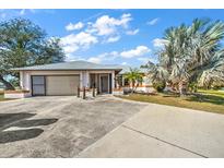 Charming single-story home featuring an attached garage, screened entryway, and mature landscaping at 19484 Midway Blvd, Port Charlotte, FL 33948