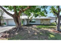 Charming home featuring an attractive stone accent wall, a well-manicured lawn, and mature shade trees at 22151 Lancaster Ave, Port Charlotte, FL 33952