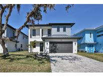 Modern two-story home with a dark gray garage door, a neutral color scheme, and tidy front yard landscaping at 2345 Oak Ter, Sarasota, FL 34231