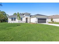 Inviting single-story home with a well-manicured lawn, a two-car garage, and modern architectural accents at 2388 Armenia Rd, North Port, FL 34286