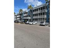 Exterior view of building with parking lot and tropical landscaping on a sunny day at 2755 Coconut Bay Ln 1K # 119, Sarasota, FL 34237